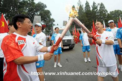 Torchbearer Zhang Hongxin (R) passes the flame to the next torchbearer Qi Hong (L) during the last-day of Beijing Olympic Games torch relay in Beijing, China, Aug. 8, 2008. (Xinhua)