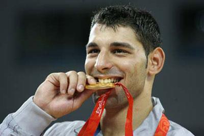 Andrea Minguzzi of Italy bites his gold medal during the awarding ceremony of the men's Greco-Roman 84kg final at the Beijing 2008 Olympic Games wrestling event in Beijing, China, Aug. 14, 2008. Andrea Minguzzi beat Zoltan Fodor of Hungary and grabbed the gold medal. (Xinhua Photo/Lu Mingxiang)