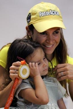 Olympic long jump gold medallist Brazilian Maurren Higa Maggi (R), shows her medal next to her daughter Sophia during a press conference upon her arrival from the Beijing Olympic Games, in Sao Paulo, Brazil, on August 26, 2008. Maggi became the first Brazilian female athlete to win an olympic gold medal in an individual competition. [Agencies]