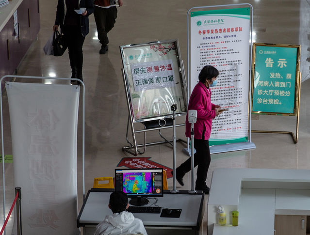 3月19日，武漢協和醫院內門診樓出入口，仍設有體溫檢測處，使用紅外測溫儀監測出入患者的體溫。提醒有發熱症狀的患者前往發熱門診的提示隨處可見。中青報·中青網記者 李崢苨/攝