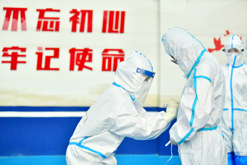 2020年7月1日，北京一街道開展新冠肺炎核酸檢測工作。醫護人員上崗前穿好防護服後在衣服上寫上名字和激勵打氣的詞語。