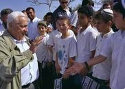 2001年5月4日，以色列總理沙龍訪問位於加沙地區古什卡蒂夫的一個猶太人定居點時和少年親切打招呼。