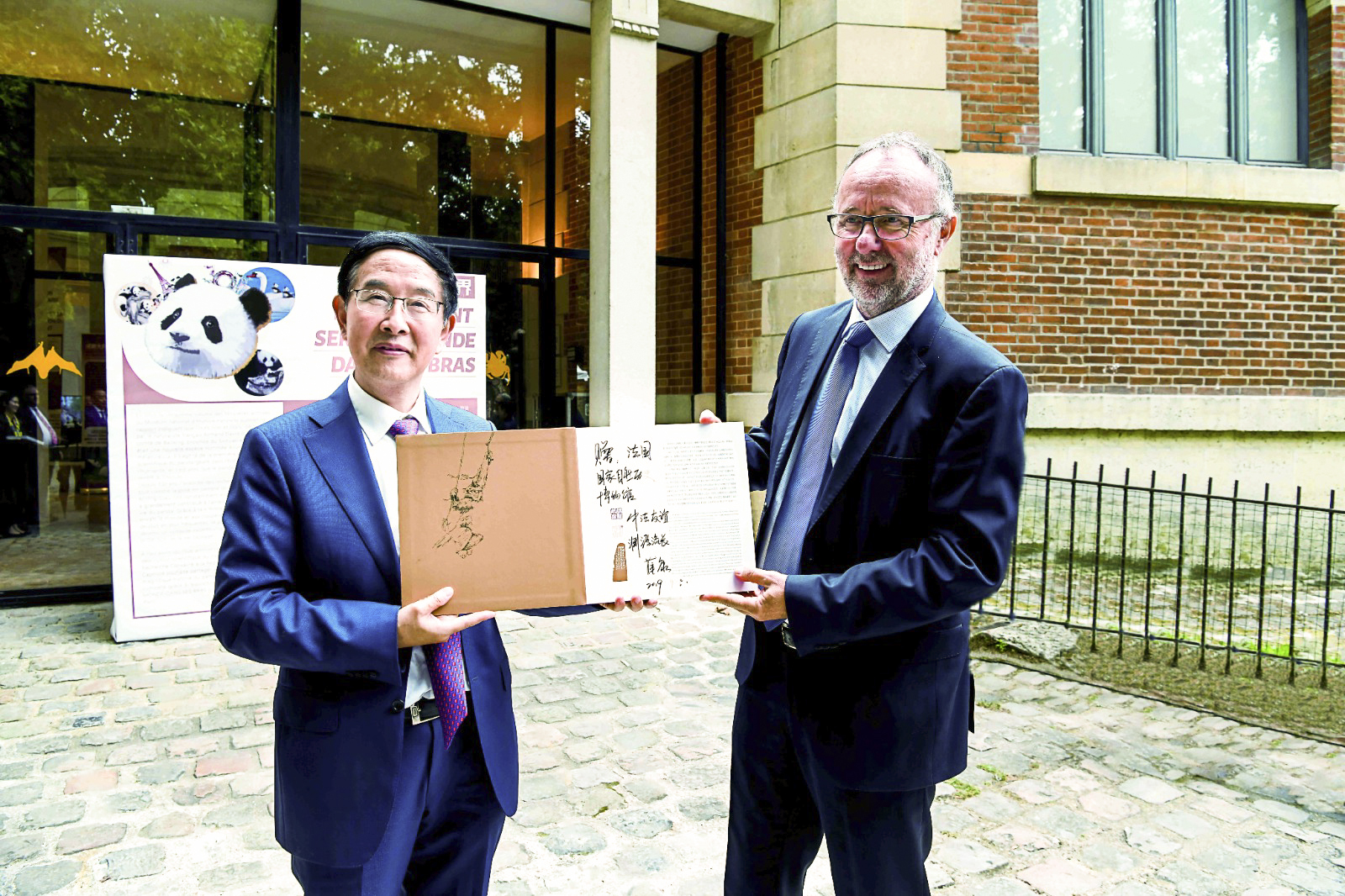 薛康（左）向法國國家自然歷史博物館館長布魯諾·戴維贈送金絲猴珍藏紀念冊
