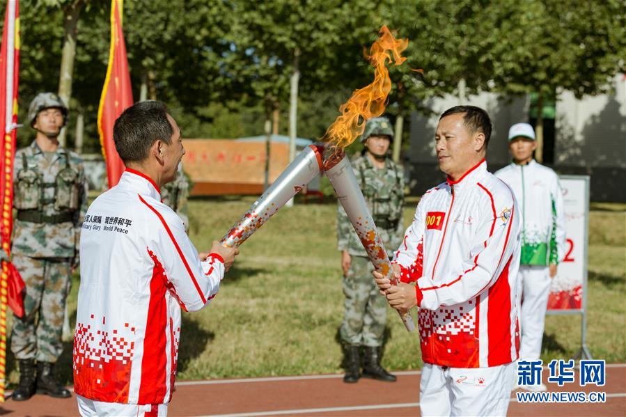 9月23日，第一名火炬手徐洪剛（前右）與第二名火炬手牛先民（前左）在火炬傳遞活動中交接。新華社發（夏先傑 攝）