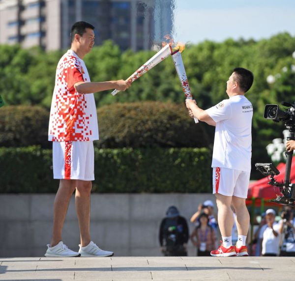 8月1日，火炬手王治郅（左）與火炬手肖東交接火炬。新華社圖