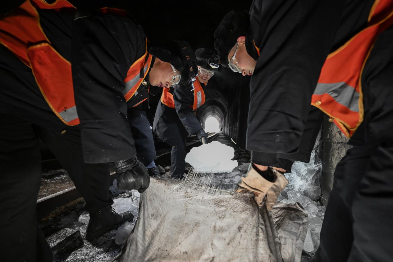 為防止擊落的冰塊二次結冰，隊員們要將幾十斤重的冰塊搬運出隧道。（圖片由太原局太原工務段趙哲昌提供）
