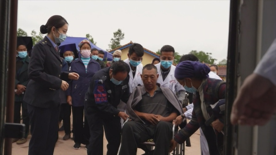 患有半身不遂的村民吉約沙果坐著輪椅前來檢查身體，工作人員把他抬到健康列車上進行診療。