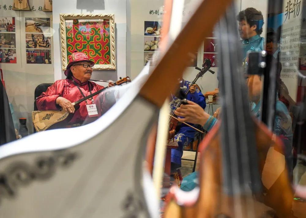在新疆美術館展館內，來自新疆博爾塔拉蒙古自治州的非遺傳承人在現場演奏民族樂器。